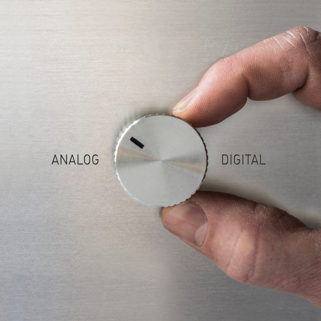 Finger dreht an einem runden Schalter von ‚Analog‘ zu ‚Digital‘